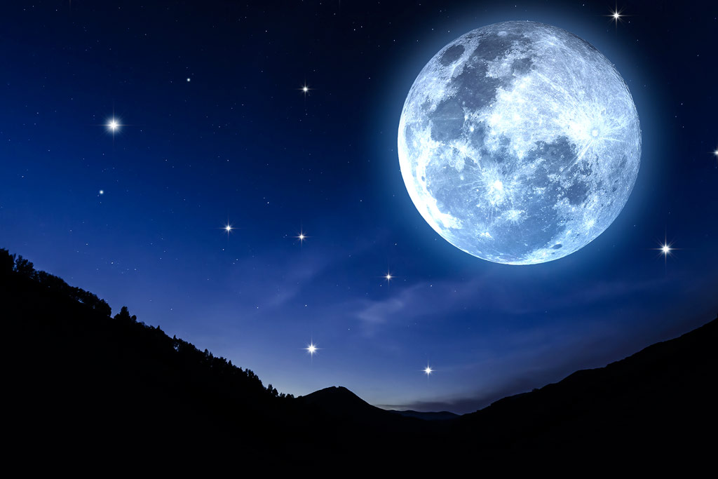 Ein überdimensional großer Mond steht über einer Landschaft.