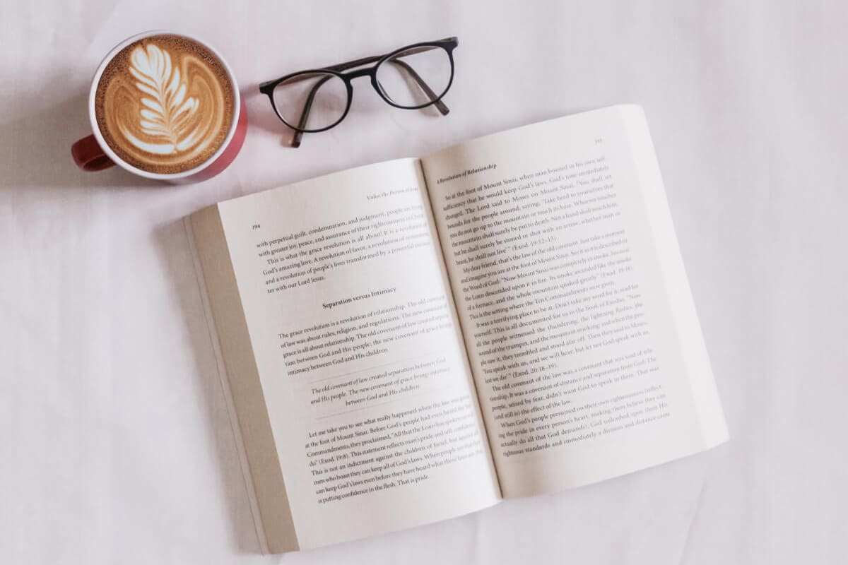 Book with coffee and glasses on table